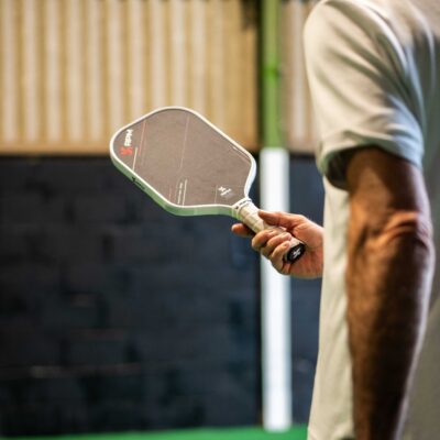A player holding a pickleball paddle on the indoor court at Foxes Farm, Essex