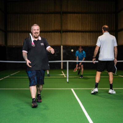 Players laughing mid game on the indoor carpeted pickleball court at Foxes Pickleball, Foxes Farm, Eight Ash Green, Colchester