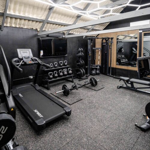 A wide view inside Foxes Gym showing free weights, machines, and cardio equipment in a converted Essex barn