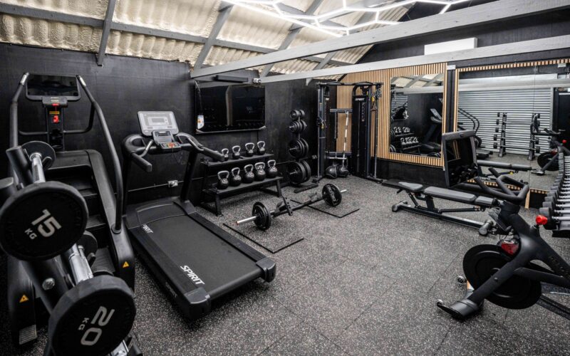A wide view inside Foxes Gym showing free weights, machines, and cardio equipment in a converted Essex barn