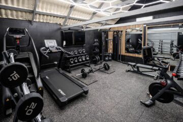 A wide view inside Foxes Gym showing free weights, machines, and cardio equipment in a converted Essex barn